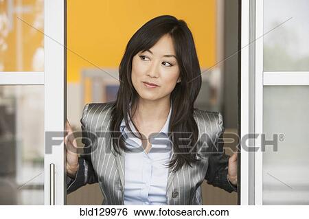 Stock Photograph - Asian businesswoman standing in doorway. Fotosearch