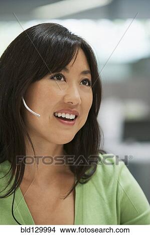 Picture - Asian businesswoman talking on headset. Fotosearch