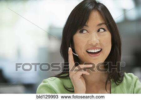 Stock Image - Asian businesswoman talking on headset. Fotosearch