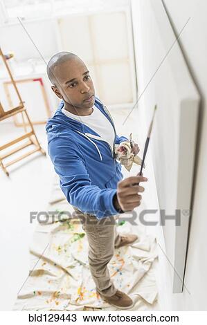 Stock Image - Black artist painting in studio. Fotosearch