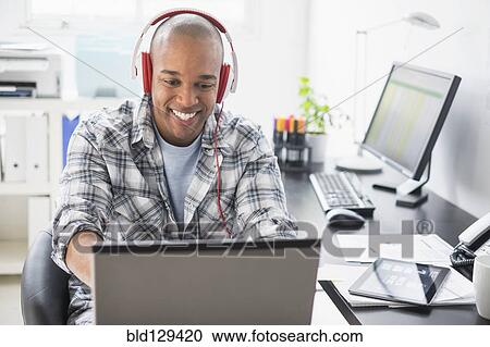 Black businessman listening to headphones in office View Large Photo Image Stock Image - Black businessman listening to headphones in office. Fotosearch