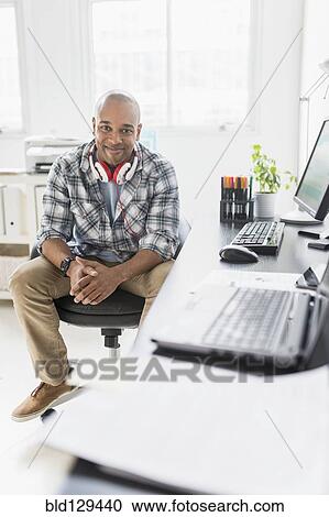 Black businessman smiling at desk View Large Photo Image Stock Image - Black businessman smiling at desk. Fotosearch
