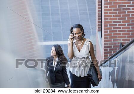 Black businesswoman talking on cell phone on escalator View Large Photo Image Picture - Black businesswoman talking on cell phone on escalator. Fotosearch