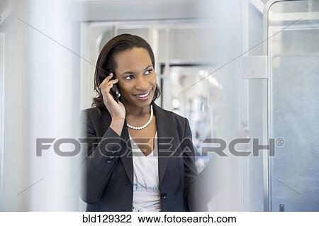 Stock Image - Black businesswoman talking on cell phone on train. Fotosearch