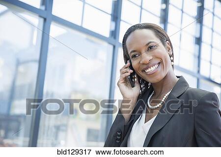 Stock Photo - Black businesswoman talking on cell phone outdoors. Fotosearch
