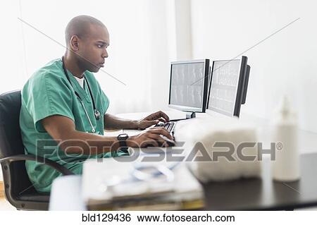 Stock Photograph - Black doctor using computer in office. Fotosearch