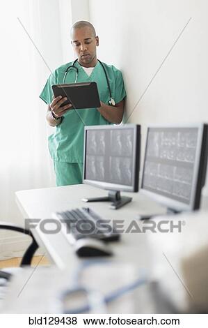 Black doctor using digital tablet in office View Large Photo Image Stock Photo - Black doctor using digital tablet in office. Fotosearch