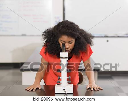 Stock Photography - Black girl using microscope in chemistry lab. Fotosearch