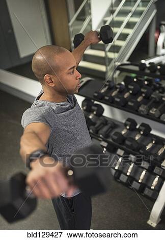 Stock Photo - Black man lifting weights in gym. Fotosearch