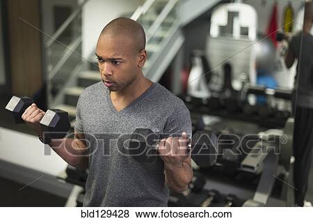 Stock Photo - Black man lifting weights in gym. Fotosearch