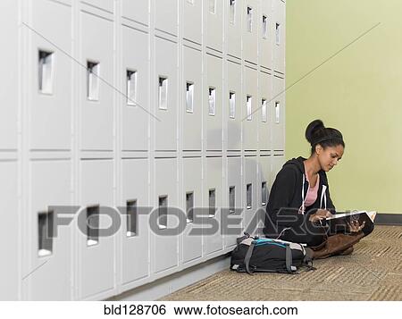 Stock Photograph - Black student reading in front of lockers. Fotosearch