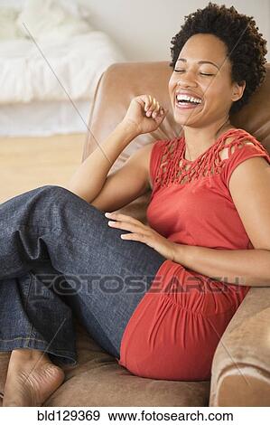 Stock Photo - Black woman laughing in armchair. Fotosearch