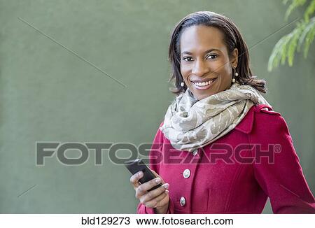 Stock Image - Black woman using cell phone outdoors. Fotosearch