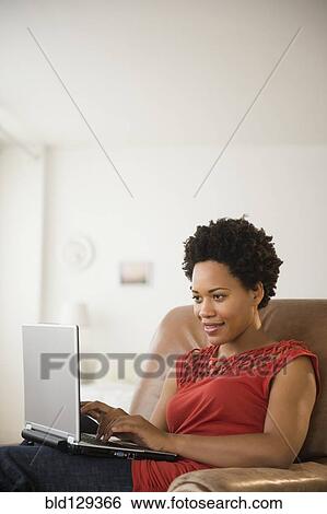 Black woman using laptop in armchair View Large Photo Image Stock Photograph - Black woman using laptop in armchair. Fotosearch