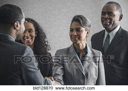 Stock Image - Business people shaking hands in meeting. Fotosearch