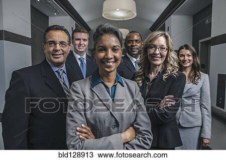 Stock Image - Business people smiling in office corridor. Fotosearch