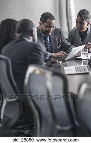 Stock Image - Business people using digital tablet in meeting. Fotosearch