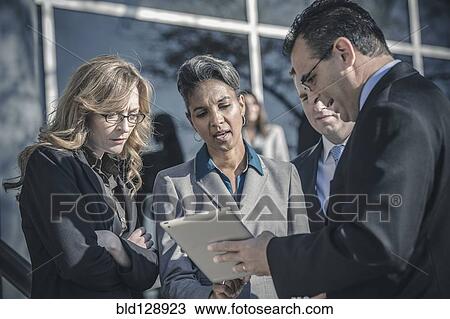 Stock Image - Business people using digital tablet outside office. Fotosearch