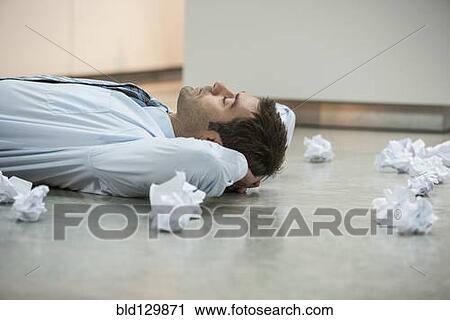 Stock Image - Businessman on floor surrounded by crumpled paper. Fotosearch