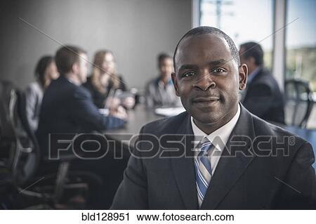 Businessman smiling in conference room View Large Photo Image Stock Image - Businessman smiling in conference room. Fotosearch