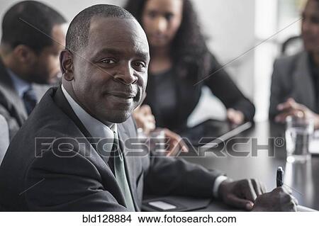 Picture - Businessman smiling in meeting. Fotosearch