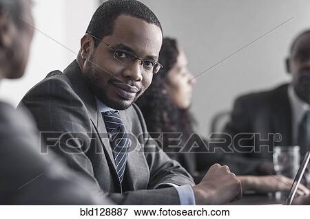Businessman smiling in meeting View Large Photo Image Stock Photo - Businessman smiling in meeting. Fotosearch