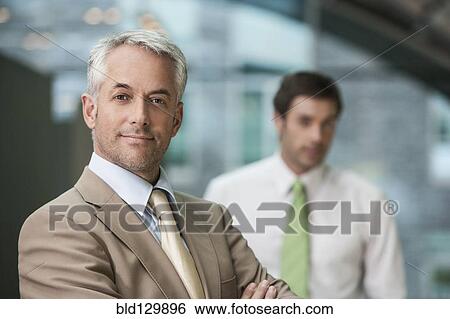 Businessman smiling in office View Large Photo Image Stock Photograph - Businessman smiling in office. Fotosearch