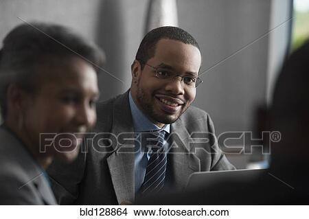 Picture - Businessman smiling talking in meeting. Fotosearch