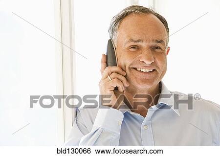 Stock Photograph - Businessman talking on phone in office. Fotosearch