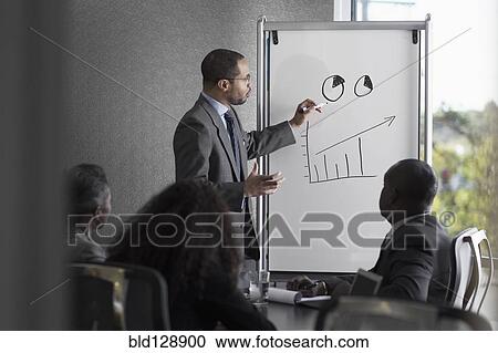 Stock Image - Businessman talking to colleagues in meeting. Fotosearch