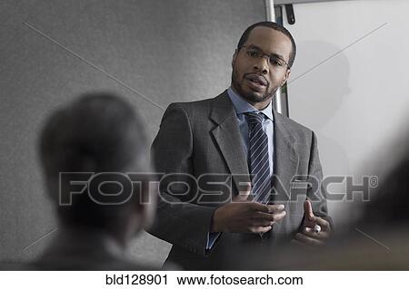 Stock Image - Businessman talking to colleagues in meeting. Fotosearch