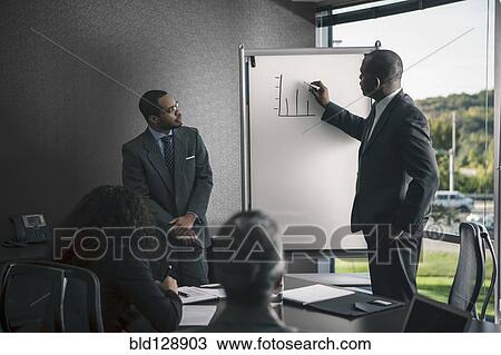 Businessman talking to colleagues in meeting View Large Photo Image Stock Image - Businessman talking to colleagues in meeting. Fotosearch