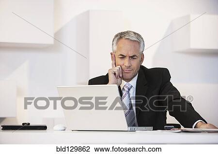 Stock Image - Businessman working at desk in office. Fotosearch
