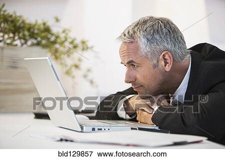 Businessman working at desk in office View Large Photo Image Stock Photo - Businessman working at desk in office. Fotosearch