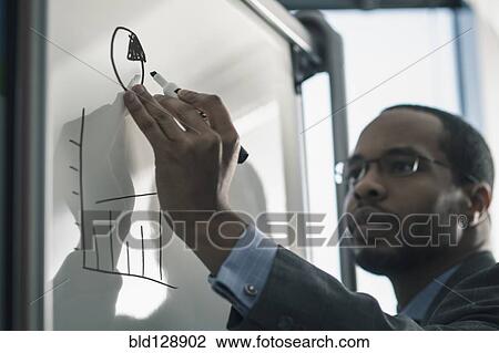 Stock Image - Businessman writing on whiteboard in office. Fotosearch