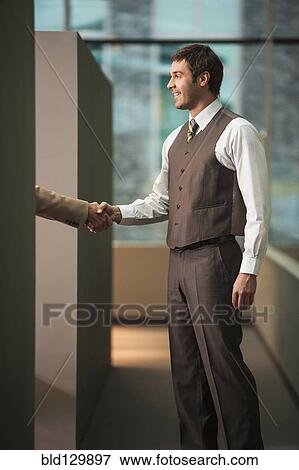 Stock Photo - Businessmen shaking hands in office. Fotosearch