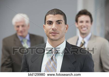 Stock Image - Businessmen standing in office. Fotosearch