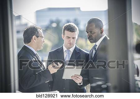 Businessmen using digital tablet outside office View Large Photo Image Stock Image - Businessmen using digital tablet outside office. Fotosearch
