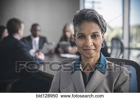 Stock Image - Businesswoman smiling in conference room. Fotosearch