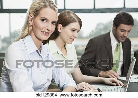 Picture - Businesswoman smiling in meeting. Fotosearch