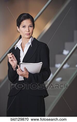 Stock Image - Businesswoman taking notes in office. Fotosearch