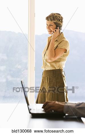 Stock Photo - Businesswoman talking on phone in office. Fotosearch