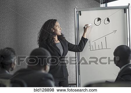 Stock Photo - Businesswoman talking to colleagues in meeting. Fotosearch