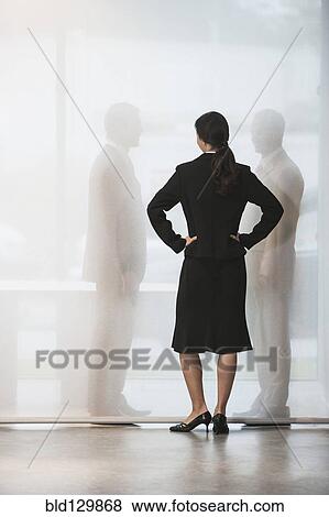 Stock Photo - Businesswoman watching colleagues shake hands behind curtain. Fotosearch