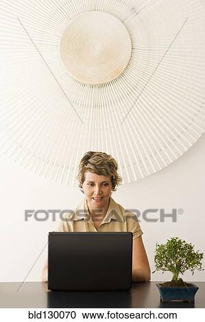 Stock Image - Businesswoman working at desk in office. Fotosearch