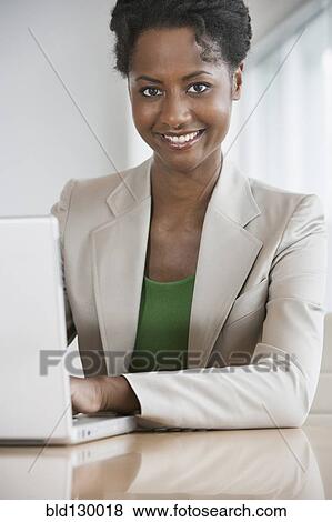 Stock Photo - Businesswoman working on laptop at desk. Fotosearch