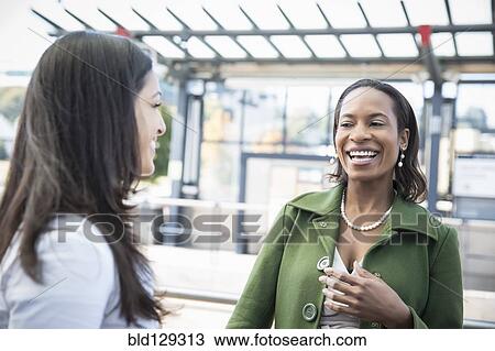 Businesswomen laughing on train platform View Large Photo Image Stock Image - Businesswomen laughing on train platform. Fotosearch