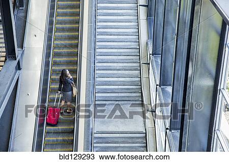 Stock Image - Businesswomen riding escalator. Fotosearch