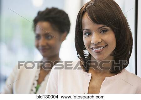 Businesswomen smiling in office View Large Photo Image Picture - Businesswomen smiling in office. Fotosearch