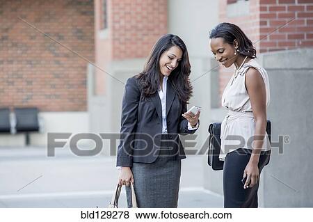 Businesswomen talking on city sidewalk View Large Photo Image Stock Photo - Businesswomen talking on city sidewalk. Fotosearch